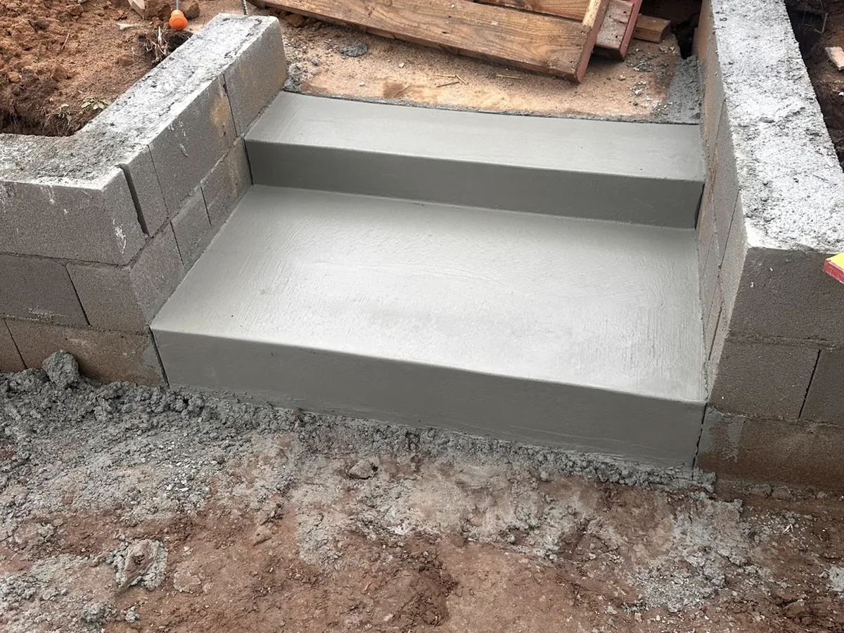New concrete steps poured between block walls on a graded site