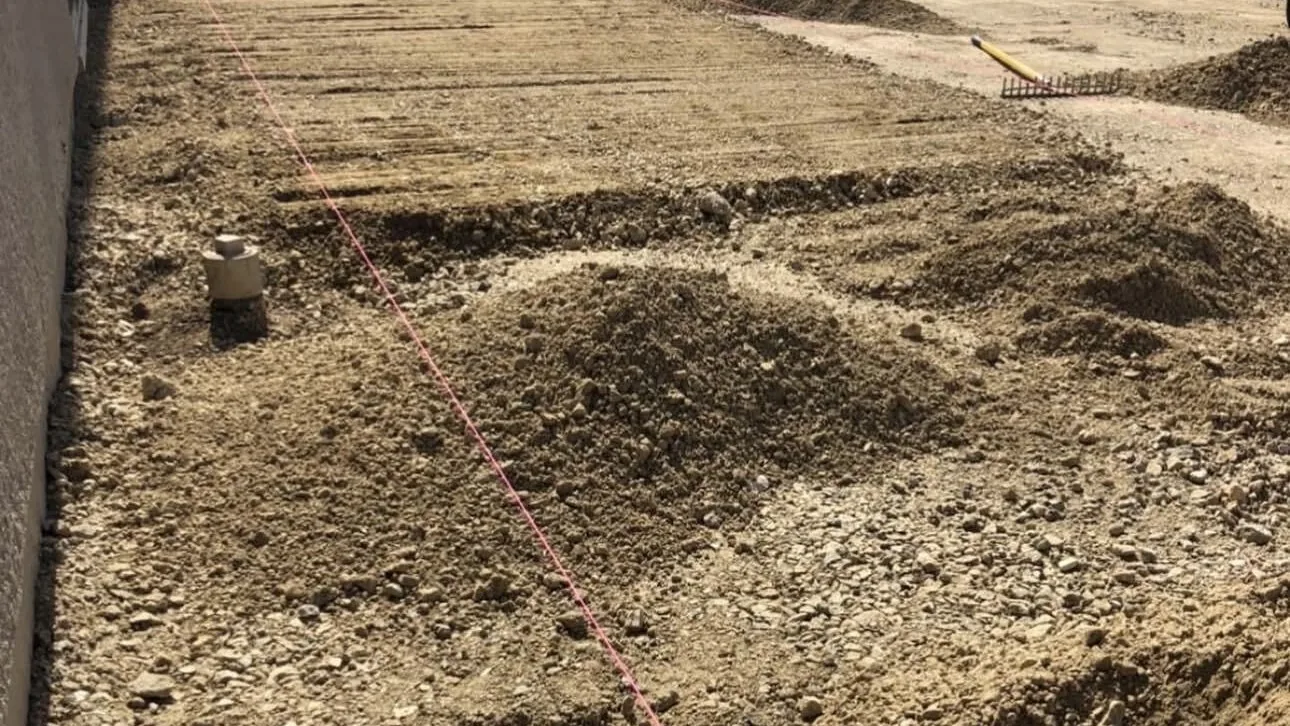 Graded and compacted base with a string line set before forming a slab