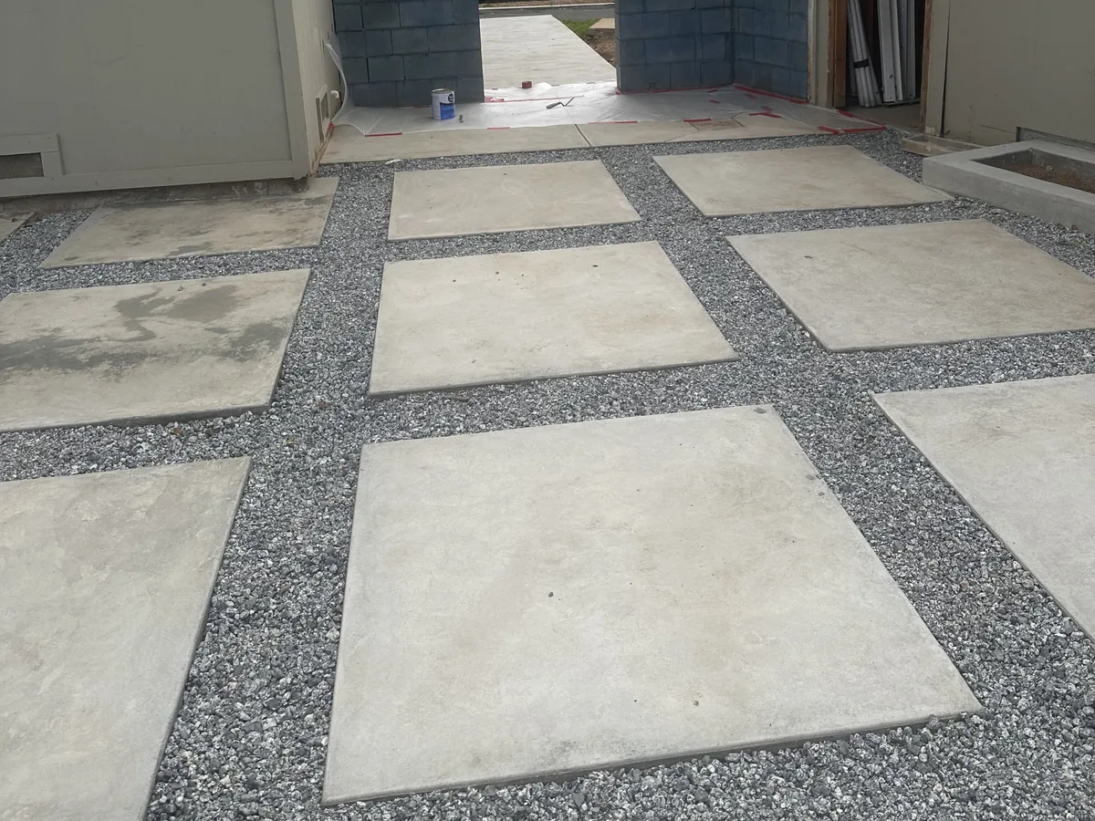 Large-format concrete pads set in gravel joints between two houses