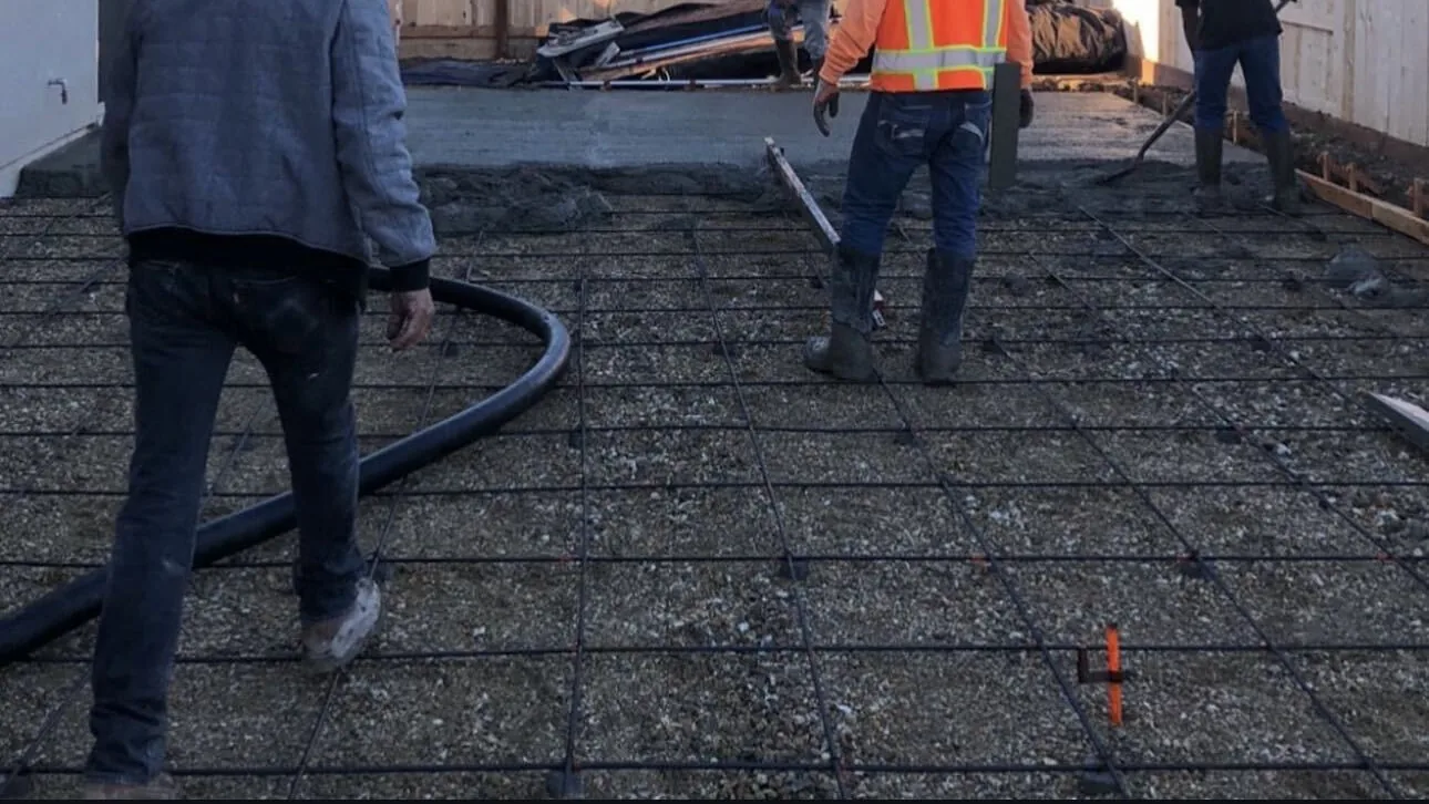 Crew placing concrete from a pump hose over a tied rebar grid