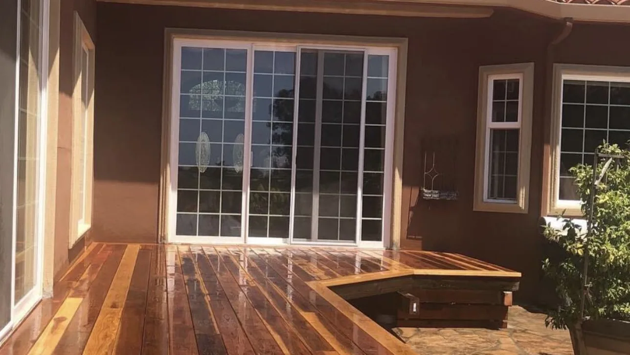 Redwood deck with a built-in bench outside a stucco home's sliding glass door