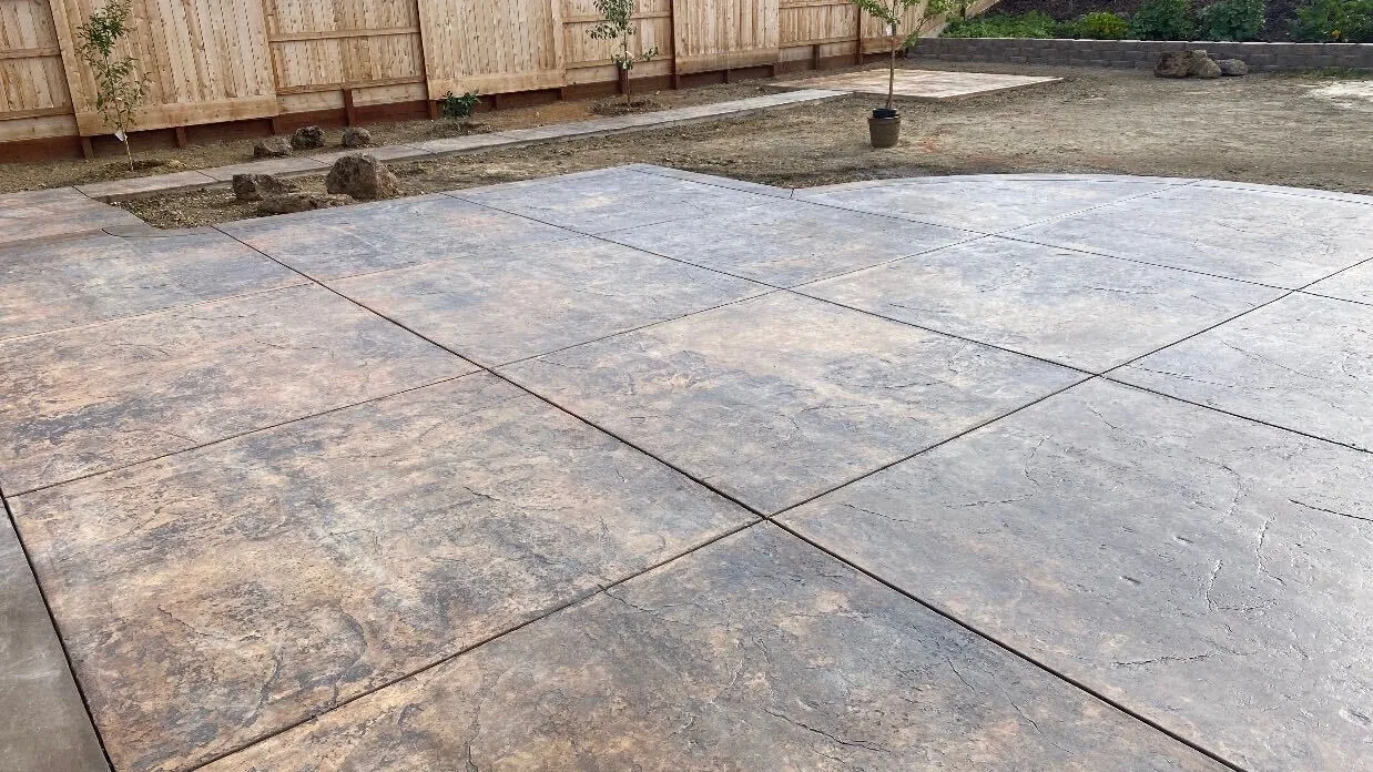 Finished colored stamped concrete patio built at ground level behind a new home