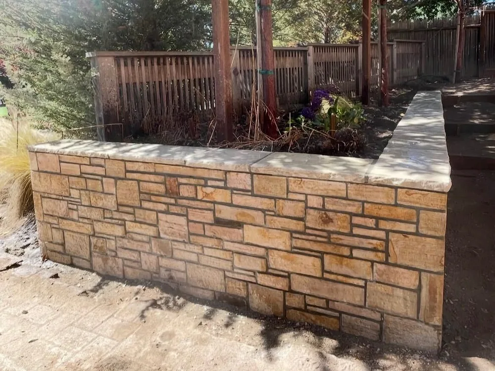 Stone veneer planter wall with a cut stone cap by Aguilar and Sons Construction