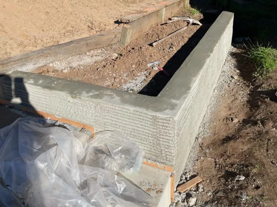 Low retaining wall with a fresh scratch coat cut into a planted hillside